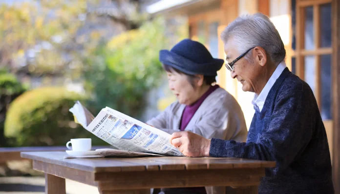 新聞紙を読む高齢者